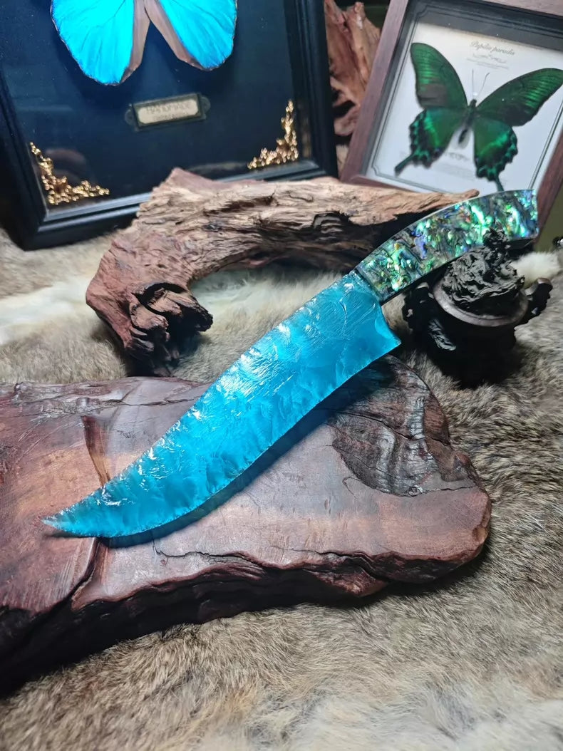 Hunting knife with a knapped stone blade, a handle made of colorful seashells, and a sky-blue cat's-eye stone blade.